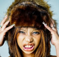 a woman wearing a fur hat with her hands on her head