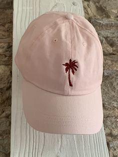 Description: Escape to a tropical paradise with our Personalised Embroidered Palm Tree Cap. This cap is a must-have accessory for beach lovers and nature enthusiasts, providing a stylish way to embrace the laid-back vibes. The front of the cap features a beautifully embroidered palm tree design, instantly transporting you to sandy beaches and sunny days. Choose from a variety of cap colours, including beige, mint green, pale blue, navy, pink, lemon, and black, to match your personal style. Personalisation: Make this cap truly unique by customising the colour of the front embroidery. Choose your preferred colour from our available options to create a cap that perfectly reflects your tropical paradise. Additionally, you can add your name or initials with our optional back embroidery. Simply Pink Cap For Vacation, Summer Vacation Baseball Cap With Curved Bill, Trendy Cotton Baseball Cap For Vacation, Beach Cotton Dad Hat, Summer Beach Visor Dad Hat, Casual Beach Dad Hat Visor, Casual Beach Visor Dad Hat, Casual Visor Dad Hat For Beach, Summer Vacation Hats With Embroidered Logo