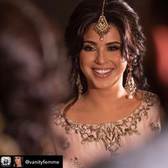 a smiling woman in a pink dress and gold jewelry