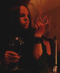 a woman sitting at a table with a glass of wine in front of her face