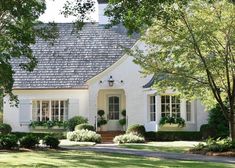 a white house with trees and bushes around it