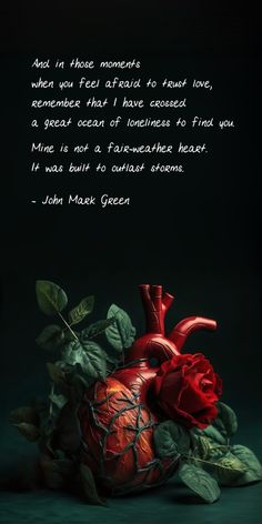 a red heart sitting on top of a green leaf covered ground next to a quote from john mack green