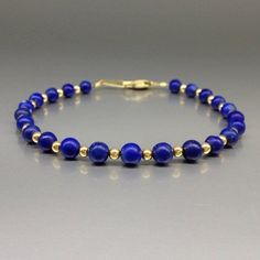 "Bracelet with polished Lapis Lazuli and gold plated beads and clasp. Unique gift for her or him, wife, friend, mother September and December birthstone, 9 year anniversary.  The dark pure natural Lapis Lazuli beads, with enclosures of pyrite and calcite, are set 1 to 1 with tiny 14K gold plated beads. The stones are strung on stainless steel and finished with a secure clasp.  All our jewelry is handmade and natural stone, slight differences and color and size may occur. All our gold plated items are Sterling silver and three times 14K gold plated. Stone size: 5 mm metal pieces: 3 mm carats: 25 Lapis Lazuli: Throughout the ages it was a symbol of royalty. The Egyptians, Sumerians and Babylonians believed it is associated with the divine feminine. Catherina the Great was a great admirer of Elegant Gold Beaded Bracelets With Natural Stones, Elegant Adjustable Blue Gold Bracelet, Elegant Blue Adjustable Gold Bracelet, Hand-strung Gold Lapis Lazuli Bracelets, Elegant Gemstone Beaded Bracelet Gift, Gold Bracelets With Lapis Lazuli And Natural Stones, Spiritual Single Strand Beaded Bracelets As Gift, Spiritual Single Strand Beaded Bracelet As Gift, Classic Natural Stone Bracelets As Gift