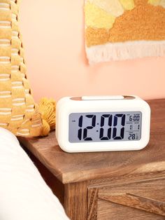 an alarm clock sitting on top of a wooden table next to a yellow rug and orange wall