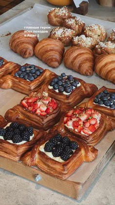 many pastries are displayed on a table with blueberries, strawberries and other fruit