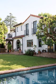 a large white house sitting next to a pool in front of a lush green yard