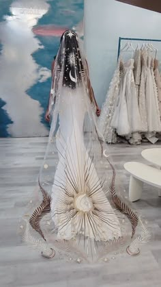 a woman in a wedding dress is walking through the room with dresses on display behind her