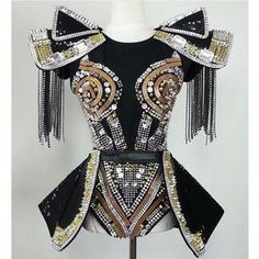 a mannequin is dressed in black and gold with fringes on the shoulders