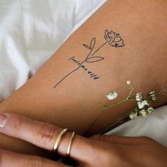 a woman's arm with a tattoo on it and flowers in the foreground