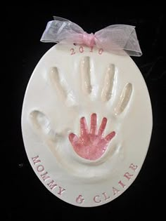 a white plate with a pink handprint on it and a ribbon around the edge