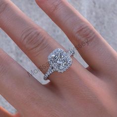 a woman's hand with a diamond engagement ring on top of her left hand