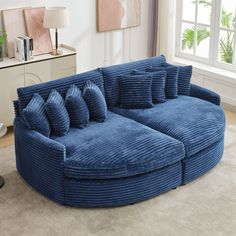 a large blue couch sitting on top of a living room floor next to a window