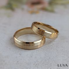 two gold wedding rings sitting on top of a table