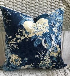 a blue floral pillow sitting on top of a wicker chair