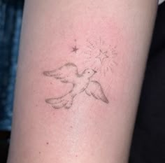 a small tattoo on the arm of a person with a dove and stars in it