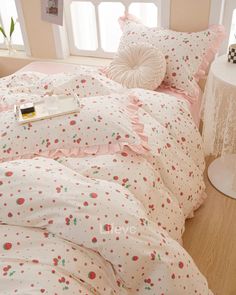 a white bed with pink and green polka dots on the comforter, pillows and pillow cases