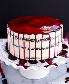 a red and white cake sitting on top of a table next to a knife, fork and spoon