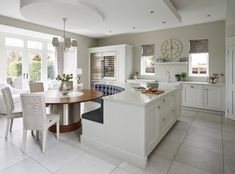 a large kitchen with white cabinets and an island in the middle, along with two dining chairs