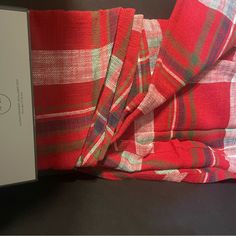 a red and green plaid blanket sitting on top of a table next to a box