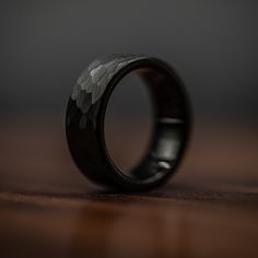 a wedding band with black wood inlays sits on a wooden table, ready to be used as a ring