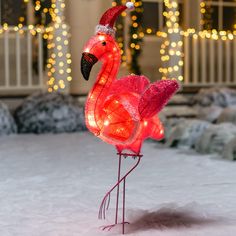 a pink flamingo standing on top of snow covered ground