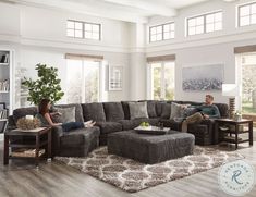 a man and woman sitting on a couch in a living room with a large ottoman