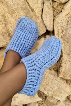 a woman's legs wearing blue knitted slippers on top of rock formations