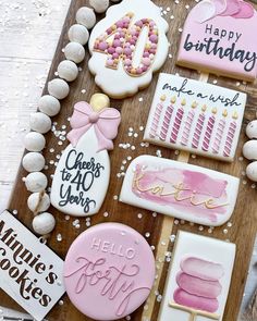 cookies decorated with pink and white icing are on a wooden board next to other decorations