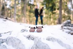 a pair of shoes sitting on top of a snow covered ground next to some trees