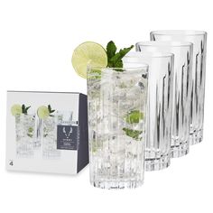 a set of four glasses with limes and mint on the side next to a box