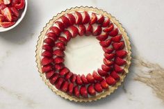 there is a pie with strawberries on it next to a bowl of strawberries