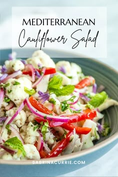 a salad with cauliflower and red onions in a blue bowl on a white table