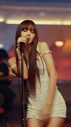 a woman with long hair holding a microphone in front of her face and standing on stage