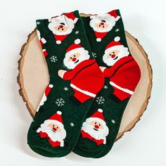 Green ankle socks with a santa claus and snowflake design. These socks are pictured on a piece of wood on a white background. Cute Christmas Gift Socks, Playful Winter Socks For Gift, Playful Winter Gift Socks, Playful Christmas Socks For Stocking Stuffers, Novelty Socks For Winter Gift, Novelty Winter Socks For Gifts, Novelty Winter Socks As Gift, Novelty Winter Socks For Gift, Fun Christmas Gift Socks