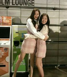 two young women standing next to each other in front of a vending kiosk