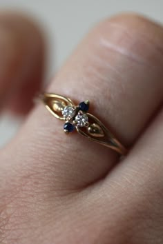 a woman's hand with a gold ring on top of her finger and blue stones in the middle