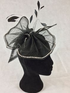 A very light and pretty headpiece with a loose bow shape made from a single layer of Sinamay on a circular black base. The entire edge of the bow is decorated with silver diamanté and there are a few black feathers for a bit of height and movement.  The solid base measures 13.5cms making it suitable for Royal Ascot.  It fixes to the head with elastic. Kentucky Derby Party Hat With Satin Bow, Elegant Black Party Hat, Elegant Hat With Satin Bow For Party, Elegant Party Hat With Satin Bow, Elegant Evening Hat With Satin Bow, Black Hat Style Headpieces For Wedding, Black Hat Headpiece For Wedding, Black Hat-style Headpieces For Wedding, Summer Party Hair Accessory With Decorative Bow