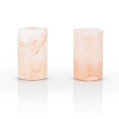 two pink rocks sitting next to each other on a white surface