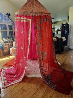 a red canopy bed sitting on top of a hard wood floor