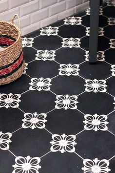 a basket sitting on top of a black and white tile floor next to a wall