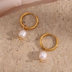 Bring some classic, luxe style to your jewelry box with these stunning Pearl Dangle Gold Hoops! These beautiful hoops feature a pearl drop element that adds a subtle, elegant touch, perfect for pairing with your most stylish outfits. Elevate your look with these timeless stunners! DETAILS & SIZE Sold as a pair Finish: 18K gold plate Materials: 316L Stainless Steel; Faux pearls Measurements: Pearls: approx. 10mm; Hoop diameter: 13mm Hinged hoops with a secure snap post closure Waterproof, tarnish Wide Flare Jeans, Bridal Aesthetic, Pearl Aesthetic, Big Hats, Cartilage Piercings, Jewelry Girl, Dainty Necklaces, Raw Crystal Jewelry, Ear Party