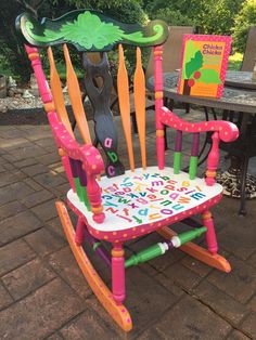 a child's rocking chair with the letters happy birthday written on it and a tree in the background