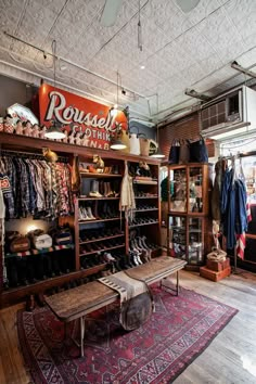 the inside of a clothing store with lots of items on shelves and a bench in front of it