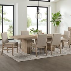 a dining room table and chairs in front of large windows with potted plant on rug