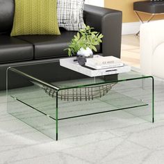 a glass coffee table sitting on top of a carpeted floor next to a couch