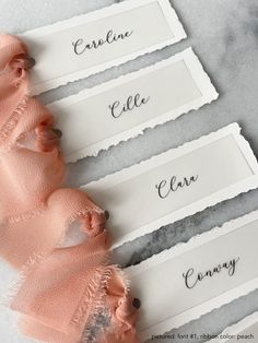 three name tags with torn edges on a marble counter top, one is pink and the other is white