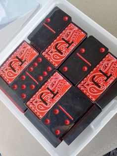 four red and black dominoes are in a plastic container on top of a table