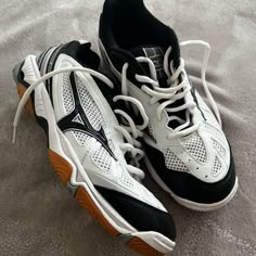 a pair of white and black tennis shoes sitting on top of a carpeted floor