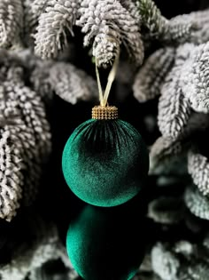 a green ornament sitting on top of a table next to some pine cones