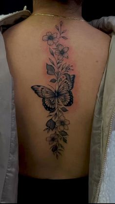 a woman's back with a butterfly and flowers on it